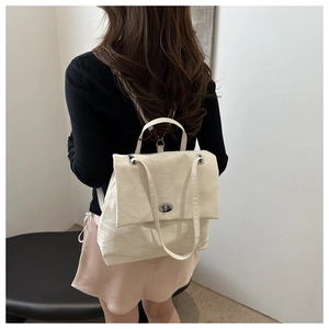 Vue détaillée du sac à dos en cuir crème montrant le fini texturé et le fermoir argenté