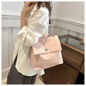 Detailed view of pink pleated leather backpack featuring a silver metal twist-lock buckle