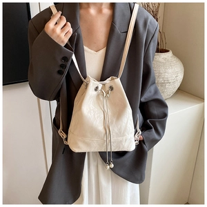 Detail view of cream drawstring bucket bag with pearl pendant and silver chain straps