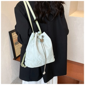 Detail of mint green drawstring bucket bag with metal butterfly and pearl charms
