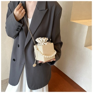Beaded handle cream woven bucket bag with drawstring closure and metal chain strap