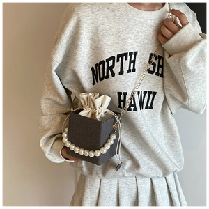 Detail of mini bucket bag with large pearl handle and beige drawstring closure