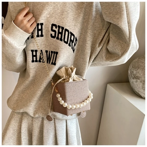 Détail d'un mini sac tissé élégant avec poignée en perles et chaîne dorée
