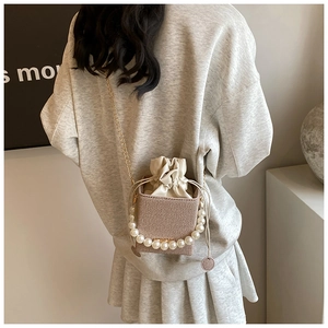 Sac seau tissé chic avec poignée en perles et bandoulière porté par un mannequin