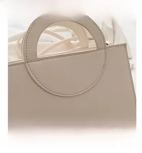 Detail view of the beige cream handbag with unique semicircular handle and fine stitching