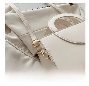 Detail of golden metal hooks and fine stitching on a beige leather shoulder bag