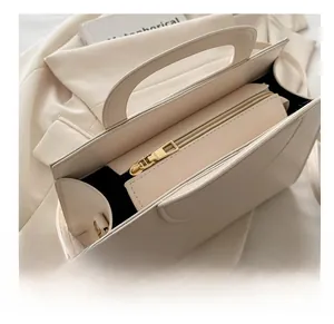Detail shot of smooth golden metal zipper and texture on beige structured handbag