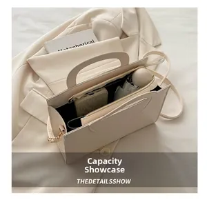 Detail view of large capacity beige crossbody bag holding a phone and folding umbrella