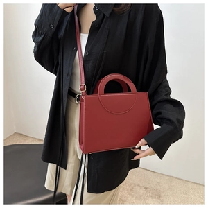 Model shot showing a deep red leather crossbody bag paired with a black shirt