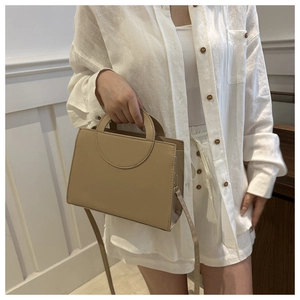 Close-up of minimalist beige leather handbag with unique circular cutout handle