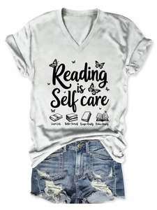 Close-up of Reading is Self care print on white V-neck T-shirt with book illustration