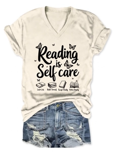 Flat lay of V-neck T-shirt with Reading is Self care print and denim shorts