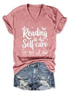 Flat lay of pink V-neck T-shirt with 'Reading is Self Care' print and denim shorts