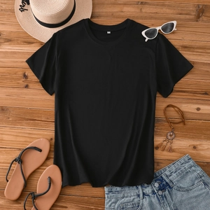 Flat lay of a black crew neck summer T-shirt with vacation accessories on wood surface