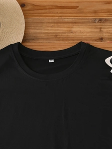 Flat lay of a black crew neck T-shirt on a wooden background with summer accessories