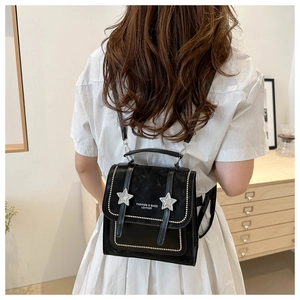 Detail view of small black retro backpack featuring star studs and adjustable straps