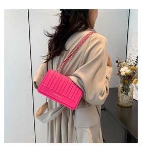 Detail of a bright pink quilted chain bag with gold hardware and woven strap style