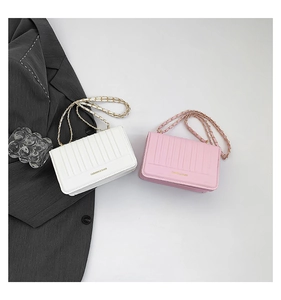 Detail of elegant quilted crossbody bags with chain straps in pink and white faux leather