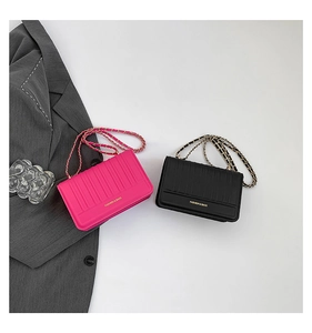 Detail of vertical textured crossbody chain bags in black and magenta with gold accents