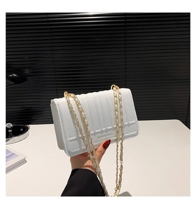Detail of white quilted handbag with gold chain strap and textured stripe pattern