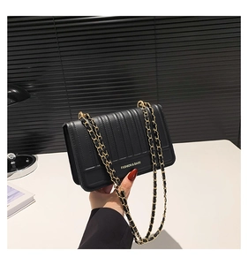Detail of black quilted shoulder bag featuring gold chain strap and fashion logo