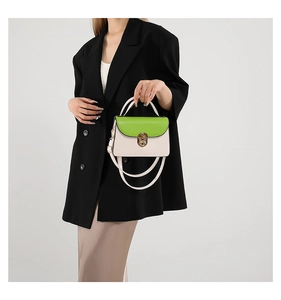 Detail of cream and green crossbody bag with gold metal clasp and top handle