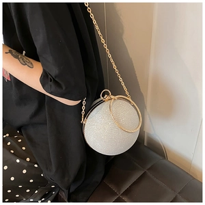 Detail view of silver glitter spherical evening bag with gold chain and ring handle