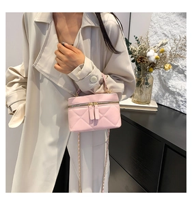 Close-up of pink quilted vanity bag with gold chain strap worn by a model