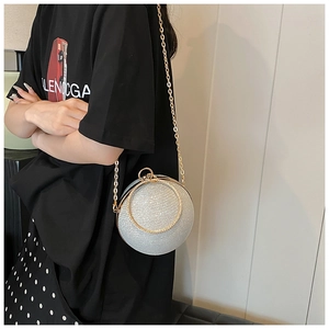 Close-up of silver spherical clutch bag with shimmering glitter and golden chain strap