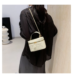 Rear view of a model wearing a white quilted mini bucket bag with gold chain strap