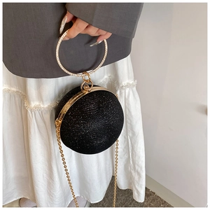 Detail of black glitter evening clutch with rhinestone round handle and gold chain