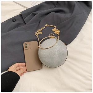 Detail of silver glitter sphere clutch bag with gold metal handle and chain strap