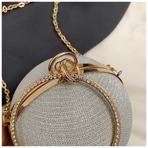 Detail of spherical evening clutch with rhinestone handle and gold metal frame