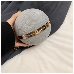 Close-up of spherical silver glitter evening bag with golden metal frame and snap closure