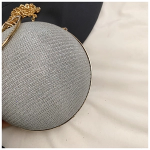 Detailed close-up of spherical evening bag with silver rhinestones and gold metal ring handle