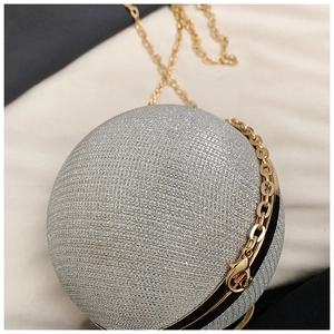 Macro shot of silver spherical clutch with gold chain and sparkling fabric texture