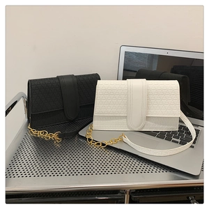 Détail de la texture géométrique et chaîne dorée sur sacs à rabat noirs et blancs
