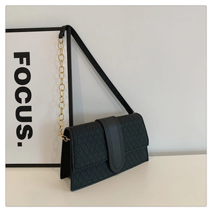 Gros plan d'un sac bandoulière noir avec motif géométrique et chaîne en métal doré