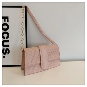 Détail de sac bandoulière rose avec texture triangle et sangle en chaîne dorée