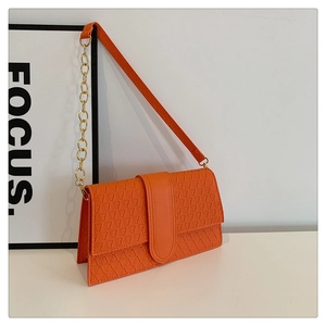 Vue détaillée du sac bandoulière orange avec texture triangle 3D et chaîne dorée