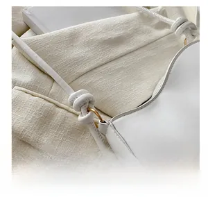 Close-up of white leather strap with knot design and golden ring metal hardware