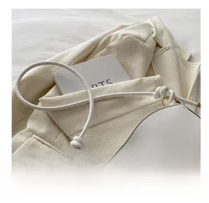 Detail of white minimalist crescent bag with stylish knotted tubular shoulder strap