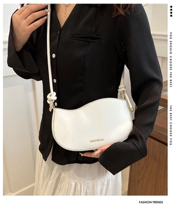 Close-up of a white wave-shaped underarm bag with matte leather and gold hardware detail