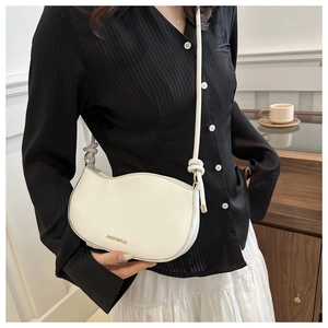 Detail of white shell bag featuring a wavy edge design and knotted shoulder strap