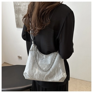 Detalle de bolso tote gris con textura arrugada y correa de cadena plateada al hombro