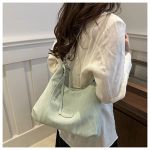 Vista dettagliata di una grande borsa tote verde chiaro minimalista indossata da una modella