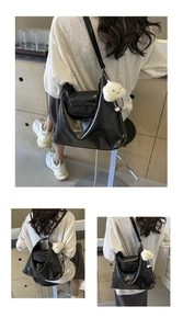 Detalle del bolso tote de cuero negro con un bolsillo de solapa y un dije de nube blanca