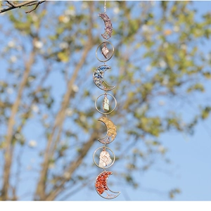 Detailed handmade crystal suncatcher with moon frame and natural raw stones outdoors