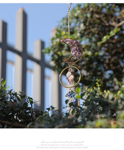 Detail of amethyst moon suncatcher with crystal stones hanging in a garden