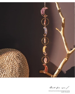 Detail of moon-shaped metal frames with natural chakra healing crystals and hanging chain